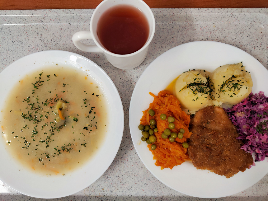 Na zdjęciu znajduje się: Jarzynowa z zacierką, Ziemniaki, Kotlet drobiowy panierowany, Sos pietruszkowy, Marchewka z groszkiem oprószana, Kompot owocowy, Surówka wykwintna z olejem